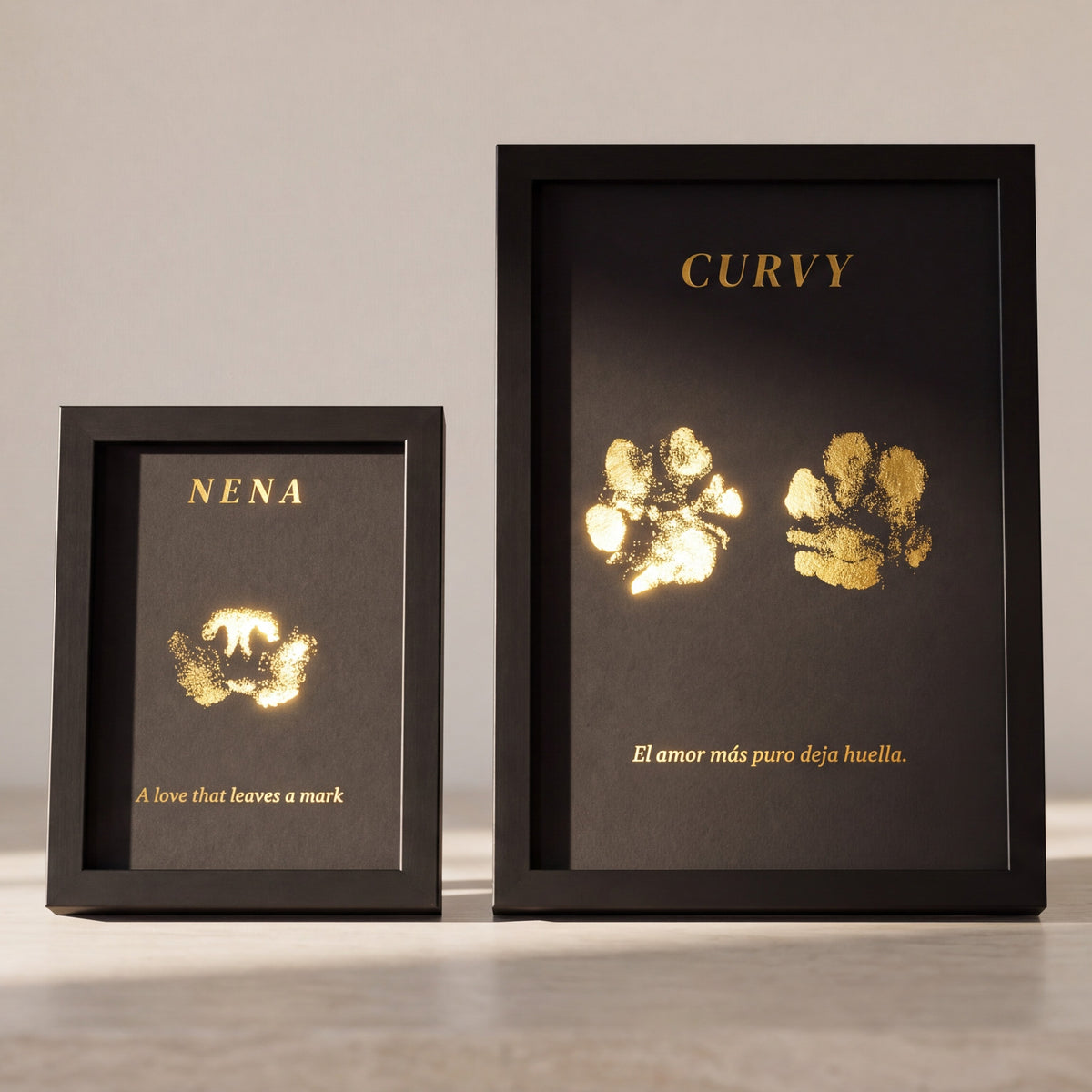PETJA print with a white frame resting on a stone worktop, with a dog's paw print in gold foil on black paper